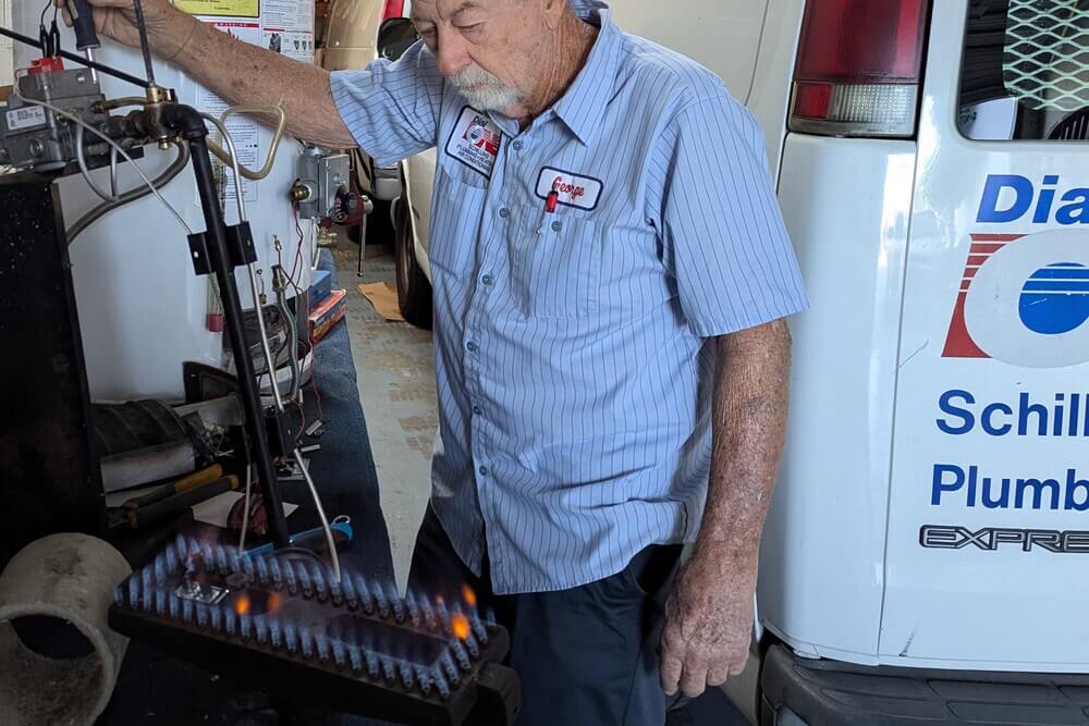 Dial ONE Schilling owner servicing a gas furnace burner assembly with visible flames.