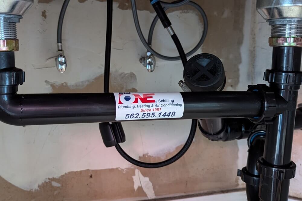 Completed under-sink plumbing installation with Dial ONE Schilling brand label.