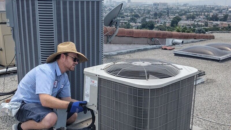 Dial ONE Schilling technician performing rooftop air conditioning maintenance on condenser unit.