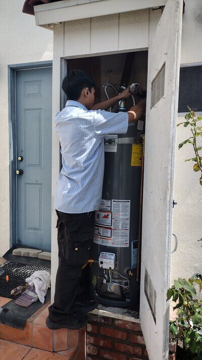 Dial ONE Schilling technician servicing a standard water heater in exterior utility cabinet.