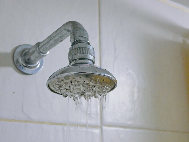 Showerhead with weak water flow due to low water pressure in a residential bathroom.