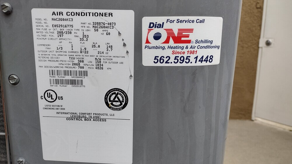 Air conditioning unit label with Dial ONE Schilling service sticker and contact number.