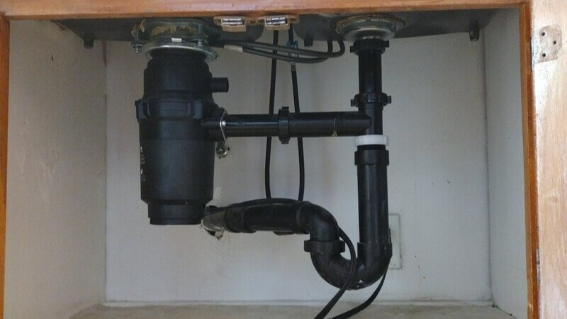 Under-sink garbage disposal and drain line representative of Dial ONE Schilling plumbing work in Signal Hill, CA