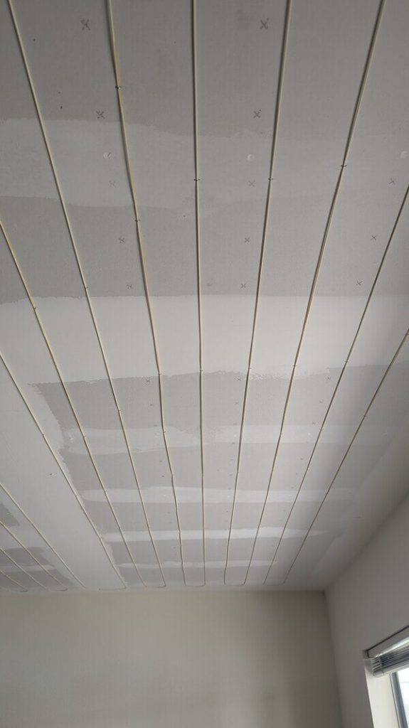 Close-up of radiant ceiling heat wires exposed during repair in a residential home by Dial ONE Schilling..