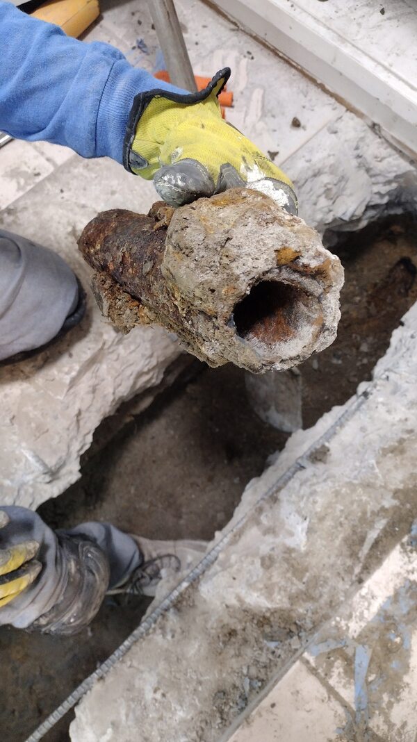 Severely corroded cast iron sewer pipe removed during trench excavation by Dial ONE Schilling.