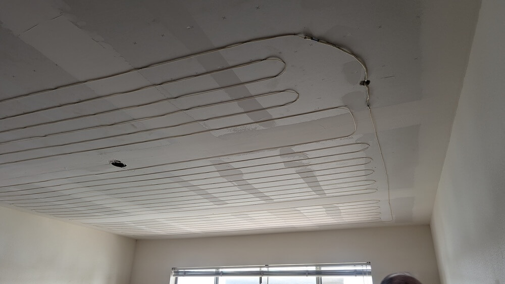 Partially exposed electric radiant ceiling heat system during repair in a residential room by Dial ONE Schilling.