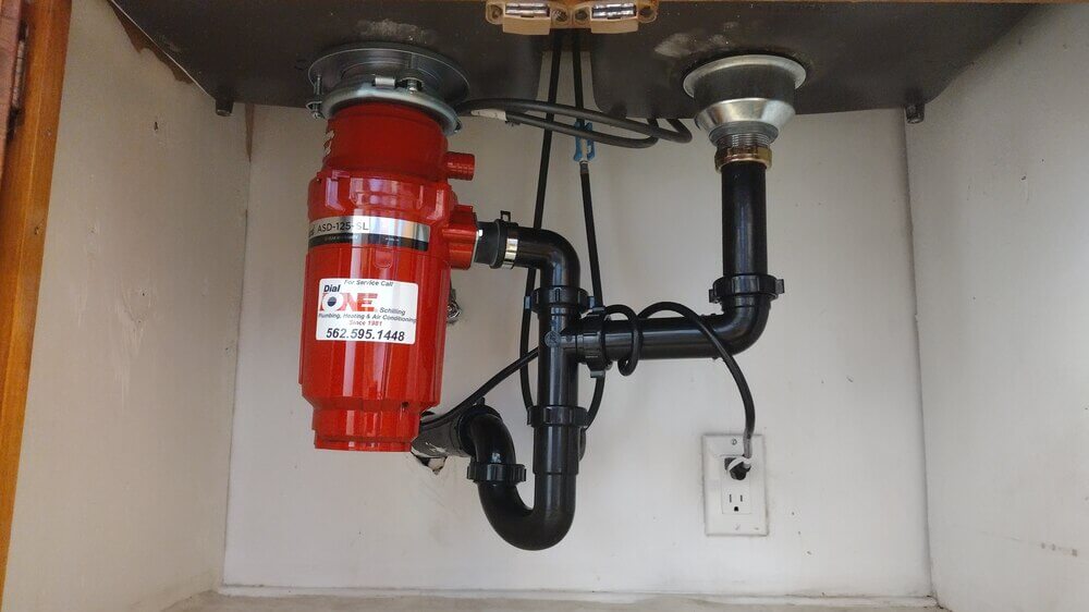 New garbage disposal installation under kitchen sink near Rossmoor, CA by Dial ONE Schilling.