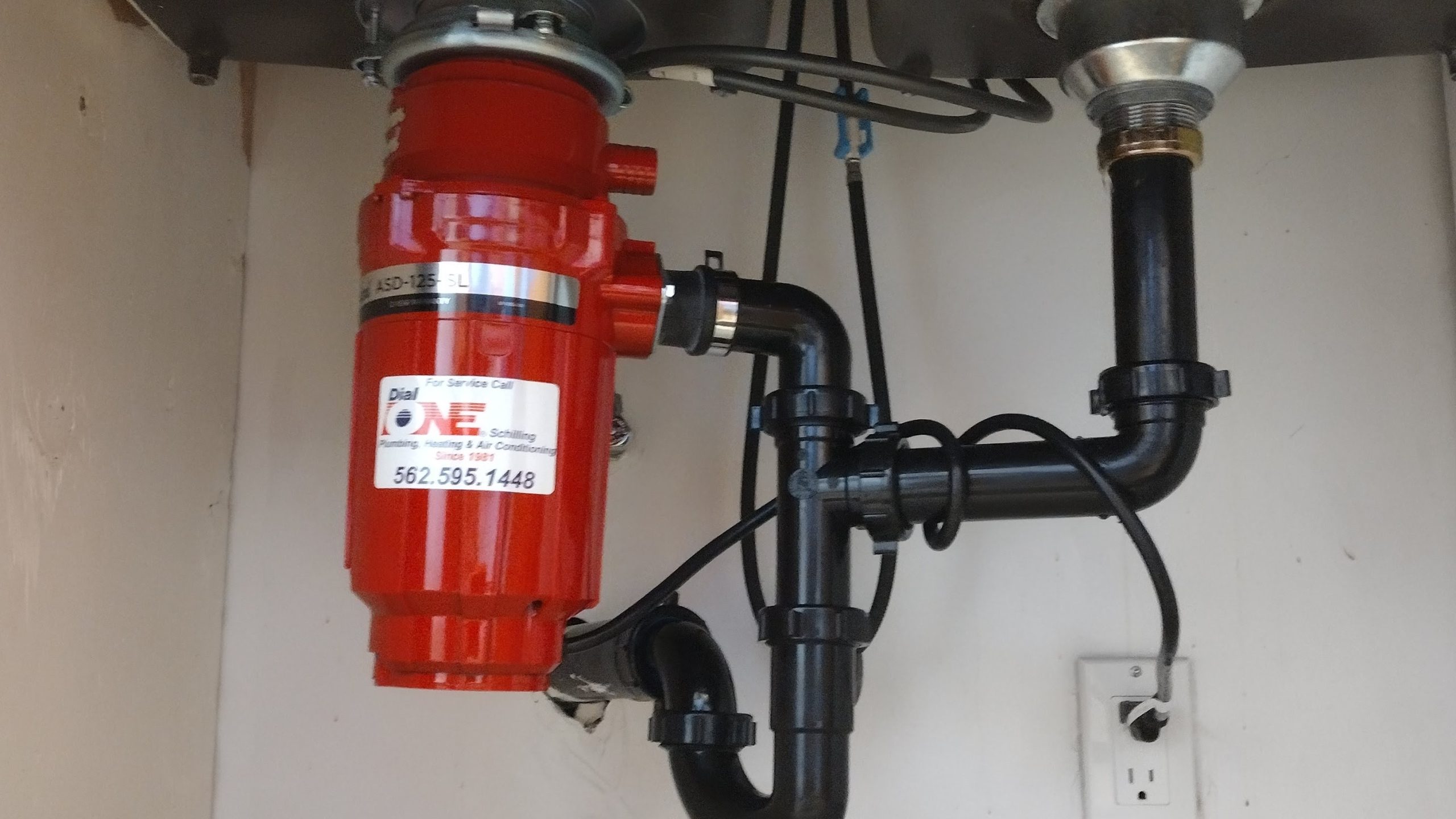 Installed red garbage disposal unit under kitchen sink in home by Dial ONE Schilling of Lakewood.