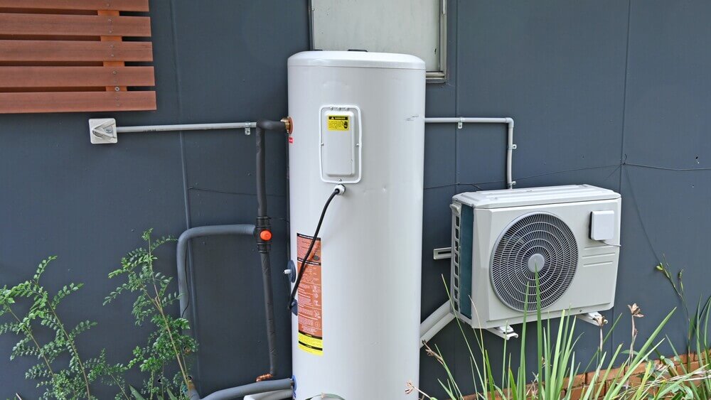 Outdoor heat pump water heater system installed next to home.