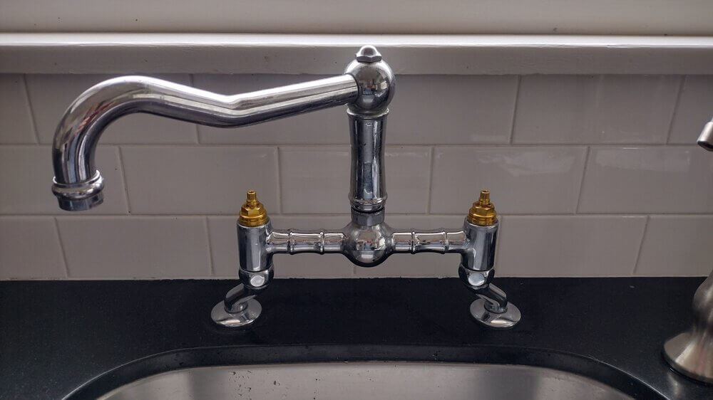 Close-up of a partially repaired kitchen faucet showing exposed valves in a Lakewood home