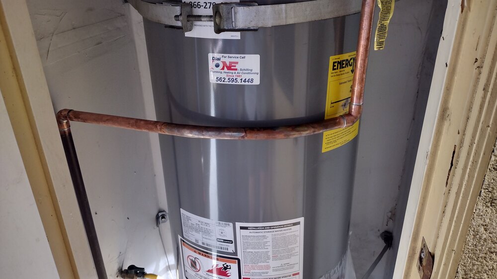 A newly installed tank water heater by Dial ONE Schilling, showing a visible service sticker, in a home in Long Beach or Lakewood, California.