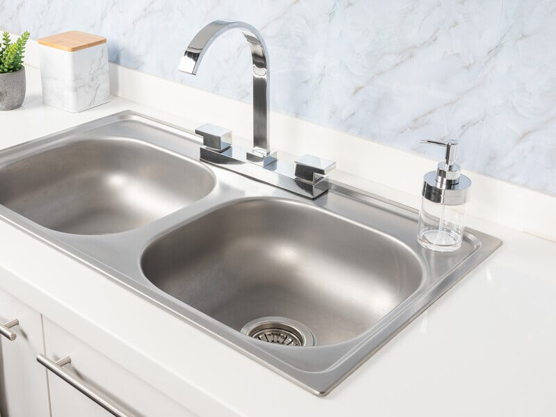 Stainless steel double-basin drop-in kitchen sink with chrome faucet