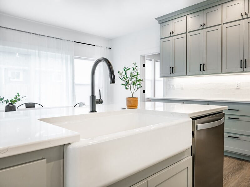 White farmhouse apron-front sink with black faucet in modern kitchen